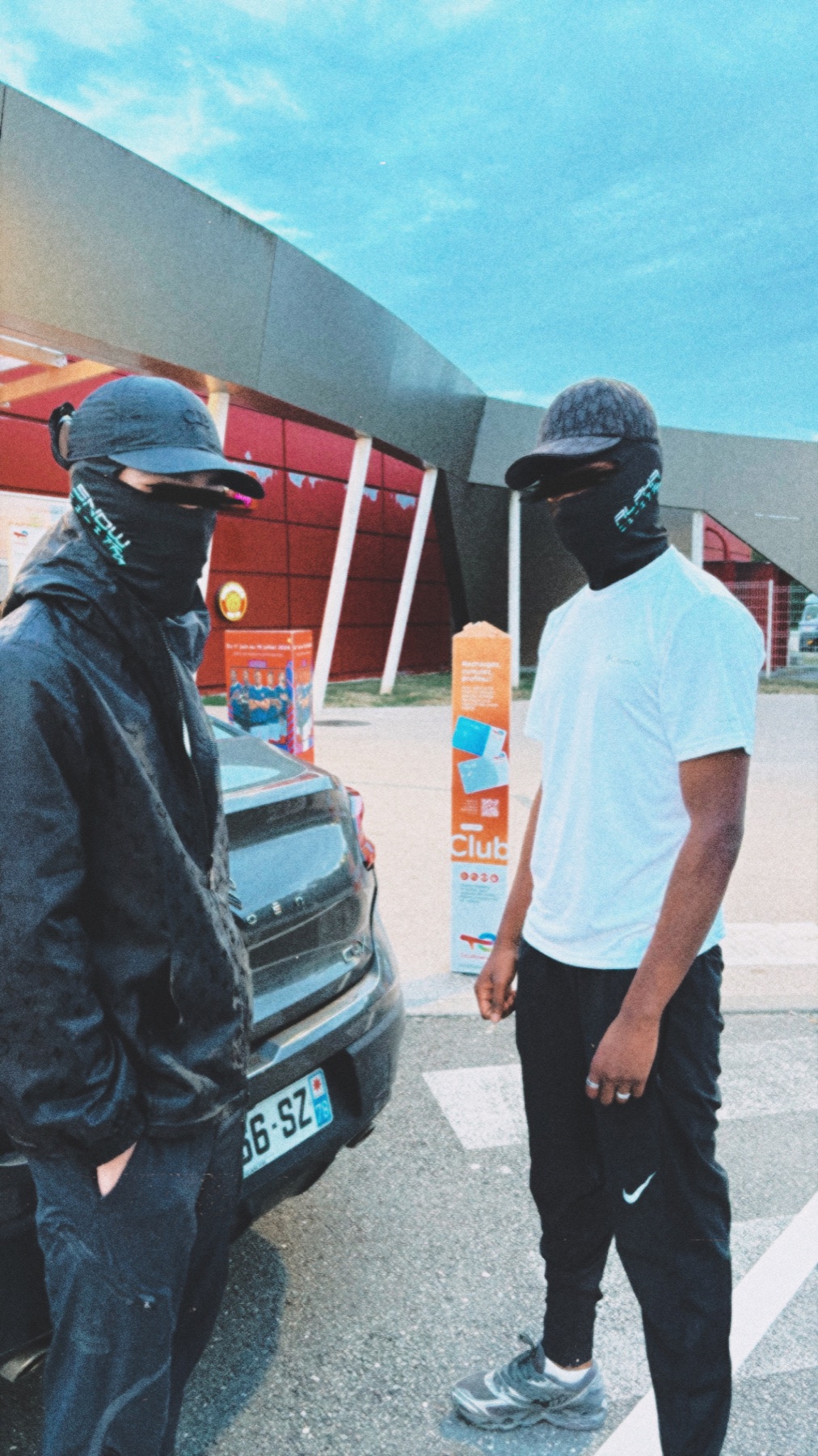 ALPHA et SNØW masqués, debout près d’une voiture
